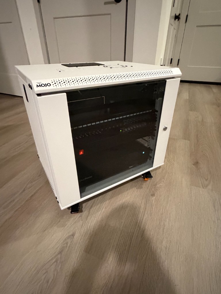 Side-angle view of compact white rack enclosure on casters with glass door closed.